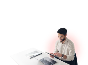 Man using a smartphone while working at a desk with a laptop